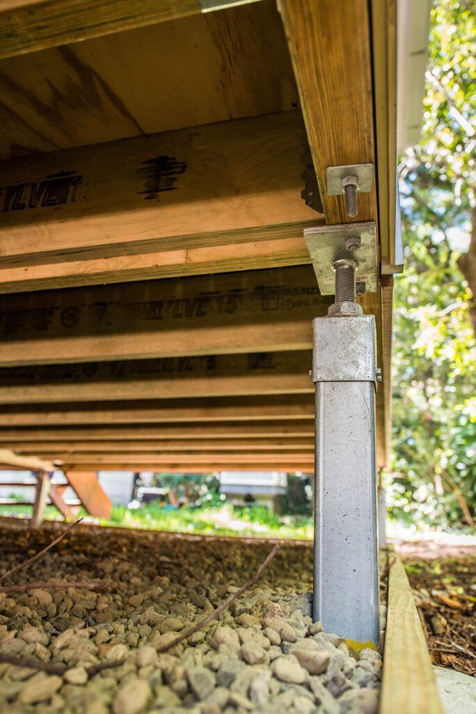 A close up of a metal post under a wooden deck.