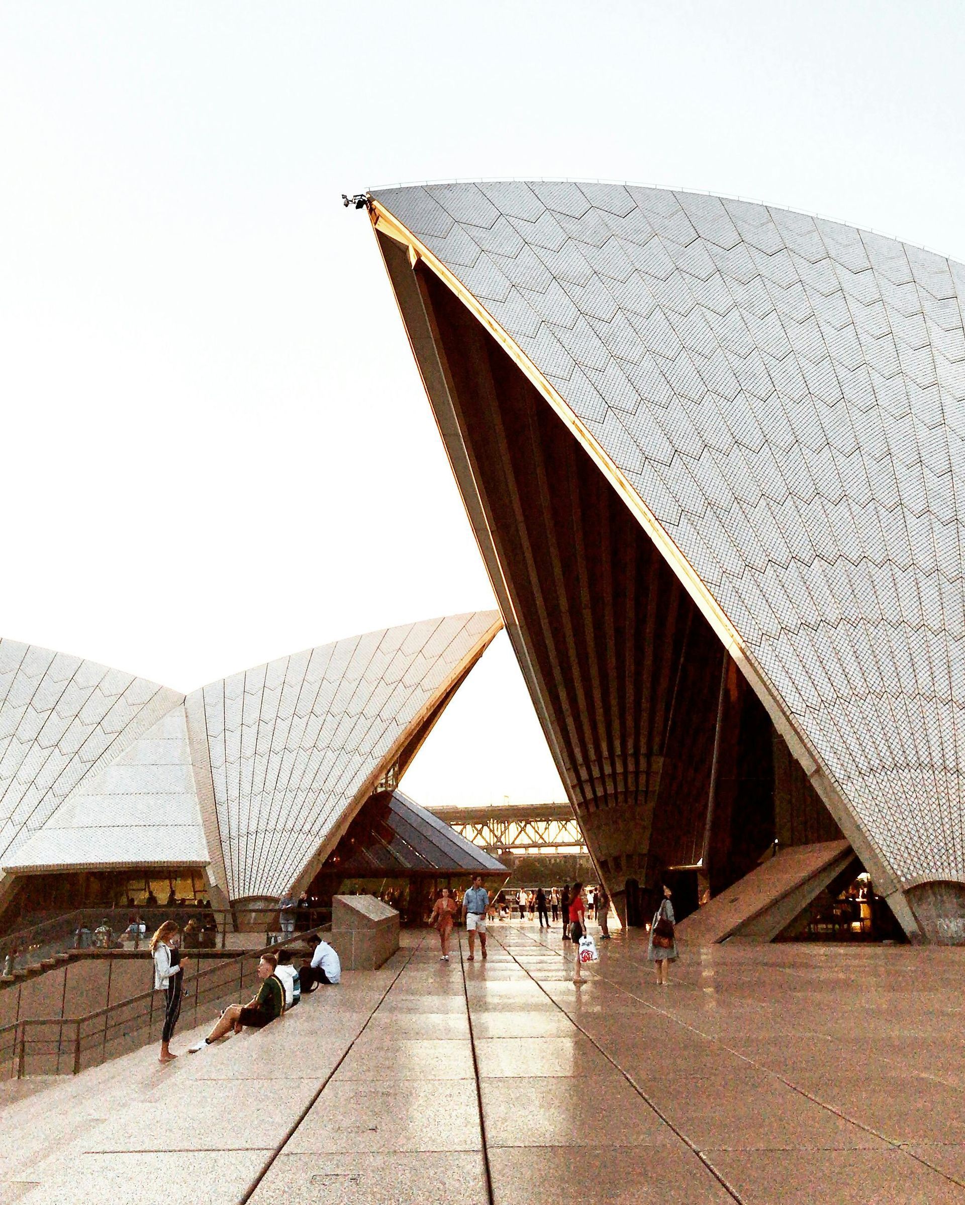 Modern curved-roof building courtyard with a few people walking on wet stone pavement