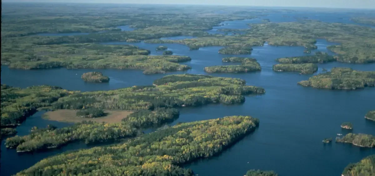 Aerial view of dense forests surrounding a complex network of interconnected blue lakes and islands.