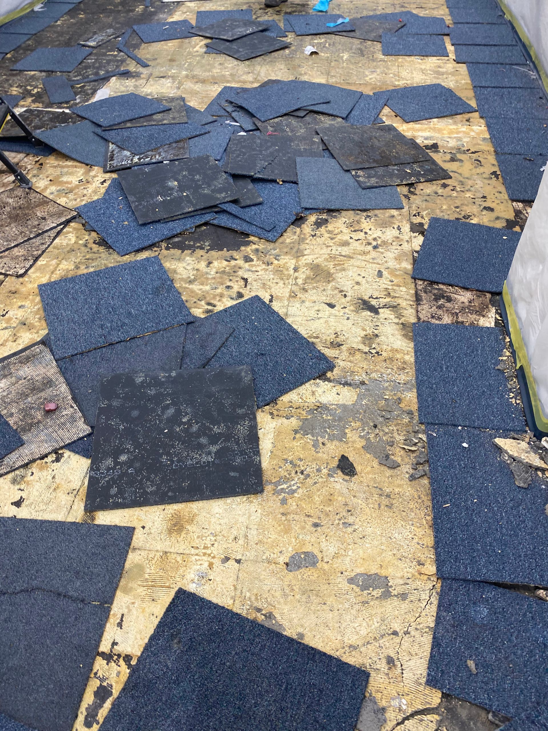Asphalt shingles removed from a roof, scattered on weathered wooden surface.