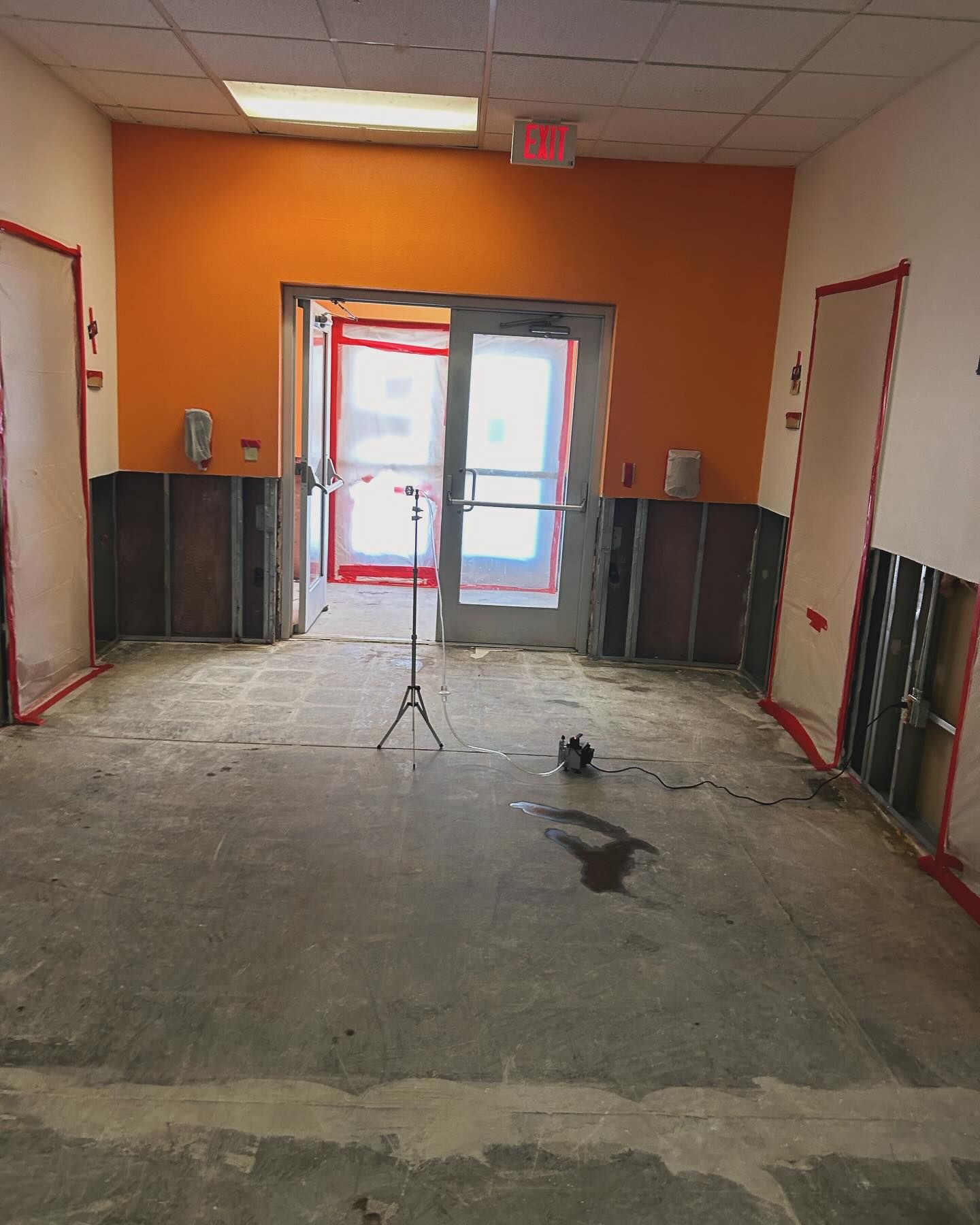 Hallway with exposed walls, orange accent wall, and door, in a construction or renovation state.