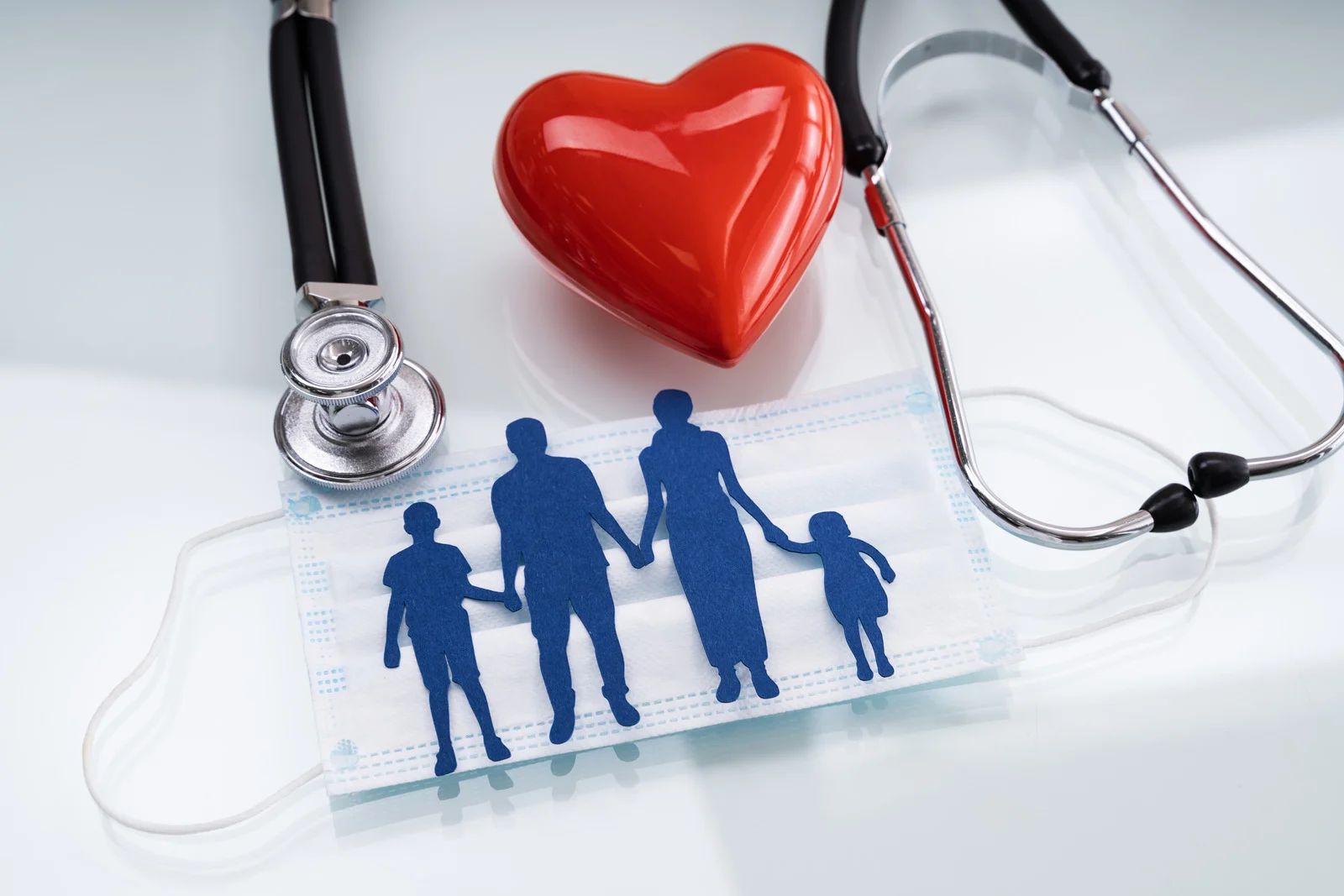 Family silhouette with red heart and stethoscope on a medical clipboard, symbolizing healthcare and insurance