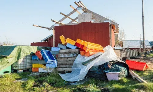 Large pile of colorful debris and wood scraps outside a shed.