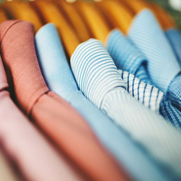 Close-up of neatly folded pastel shirts with blue, white, and coral stripes and solids