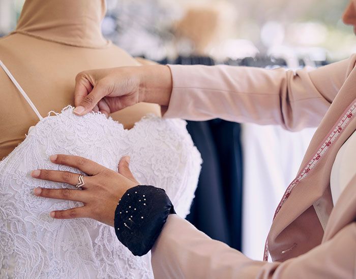 Hands adjusting a white lace dress on a mannequin in a bridal boutique