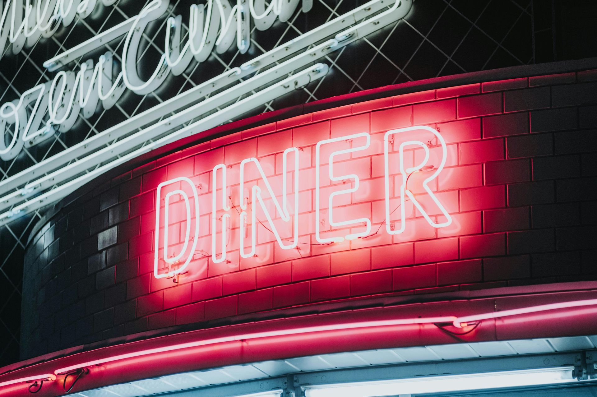 Neon pink DINER sign glowing on a curved storefront at night