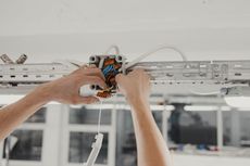 Person wiring electrical box on a ceiling. Wires and hands are visible.