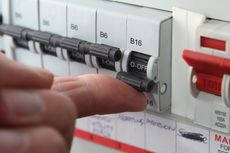 Hand turning off a circuit breaker in a fuse box.