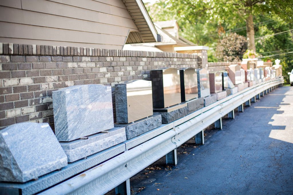 A row of gravestones are lined up in front of a brick wall.