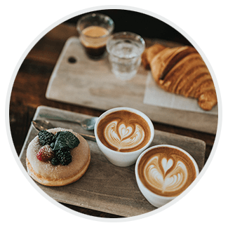 Two cups of coffee , a donut and a croissant on a table.