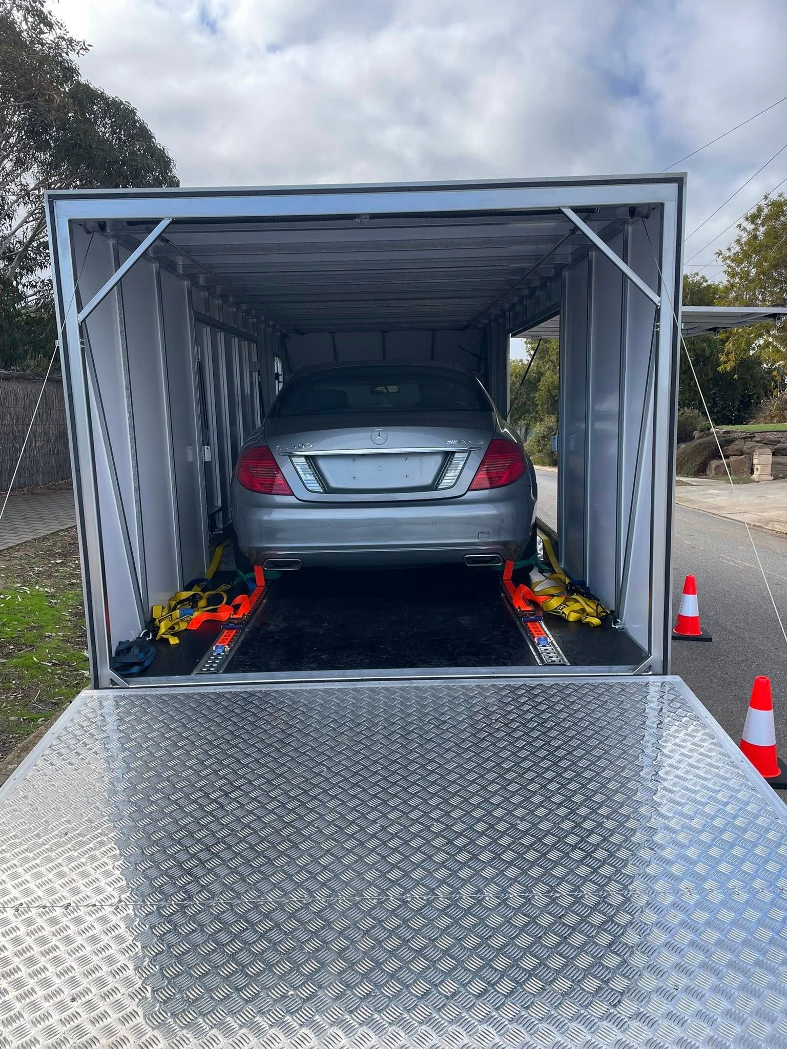 Silver Mercedes-Benz sedan inside a car-hauling trailer, secured with straps, ramp extended — Full Throttle Enclosed Car Transport in Kilmore, VIC