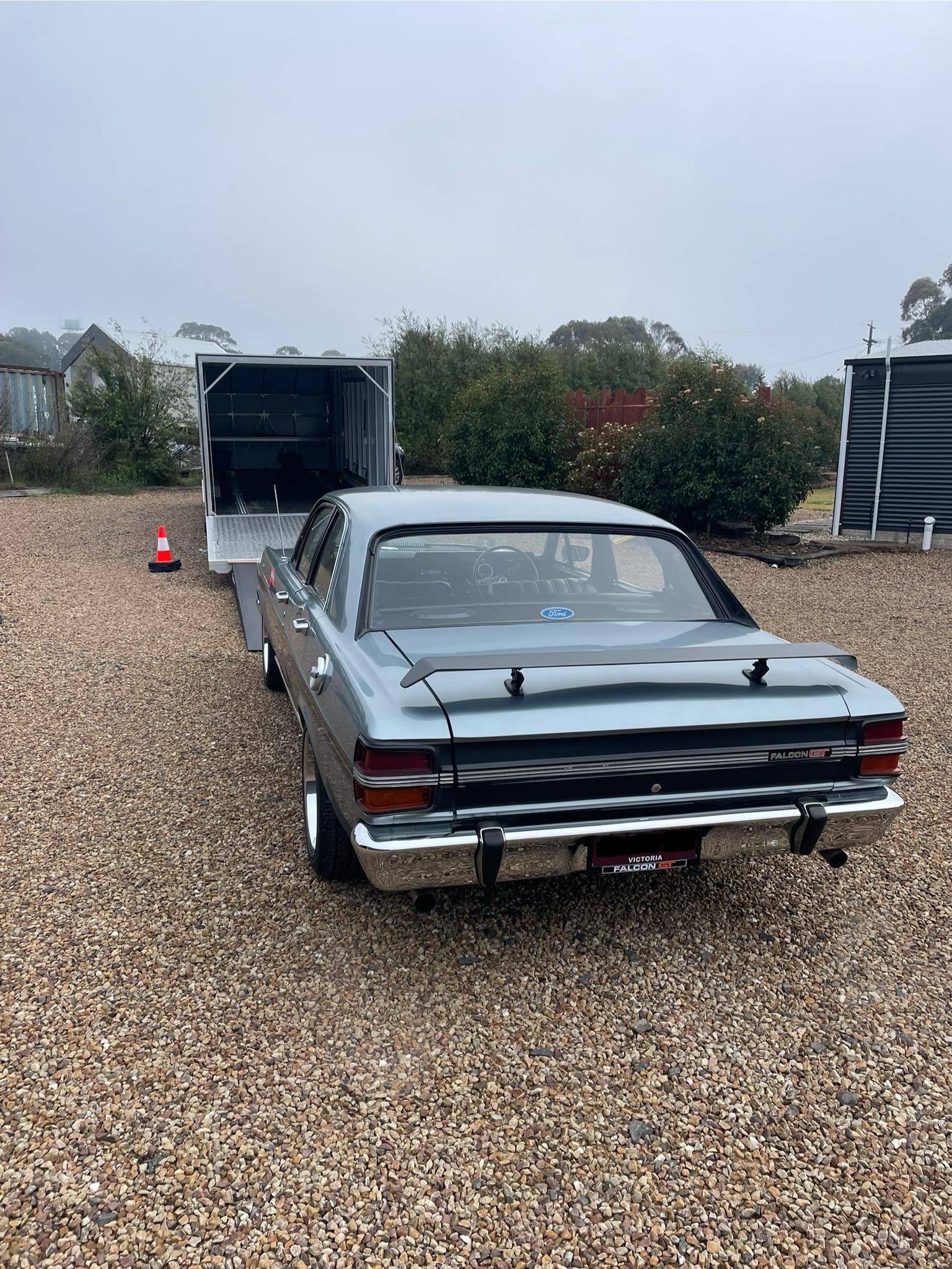 Classic Grey Car Backed onto A Trailer on A Gravel Driveway — Full Throttle Enclosed Car Transport in Sydney, NSW