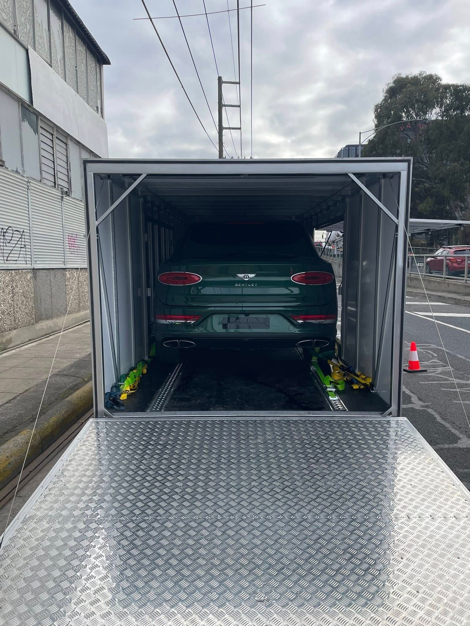 Green car inside a car hauler on a street, seen from the ramp's perspective — Full Throttle Enclosed Car Transport in Kilmore, VIC