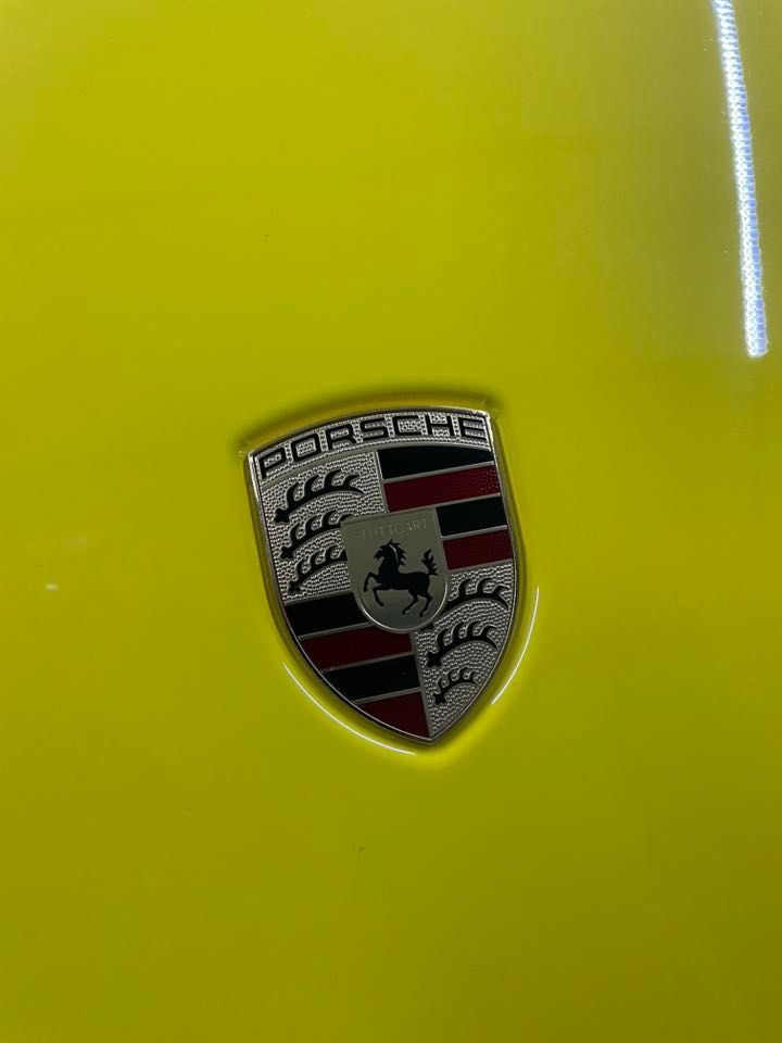 Porsche emblem on a yellow car hood — Full Throttle Enclosed Car Transport in Kilmore, VIC