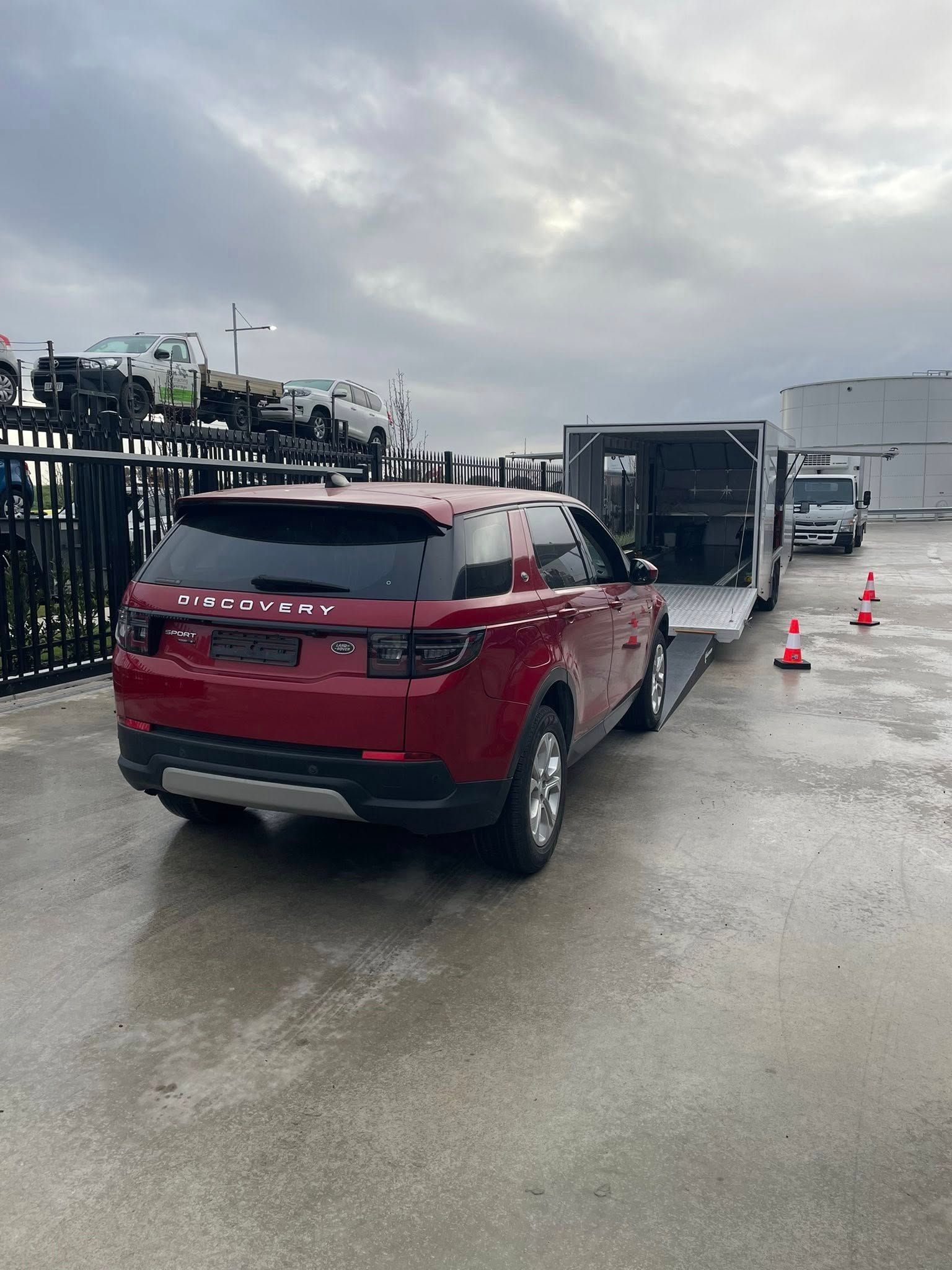 Red SUV on a car hauler in a wet parking lot — Full Throttle Enclosed Car Transport in Kilmore, VIC