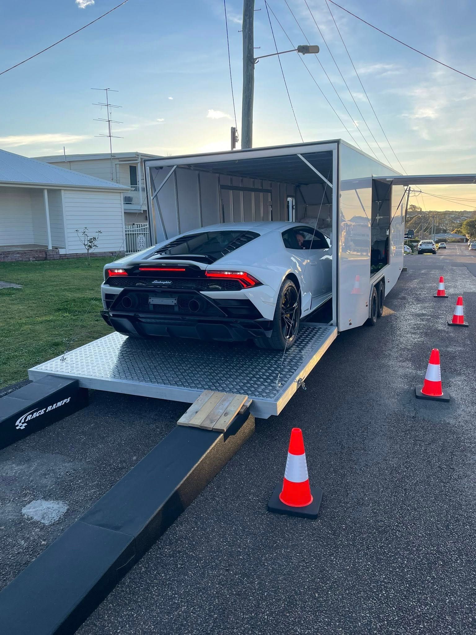 White Lamborghini being loaded into enclosed car hauler on a street, flanked by traffic cones — Full Throttle Enclosed Car Transport in Kilmore, VIC