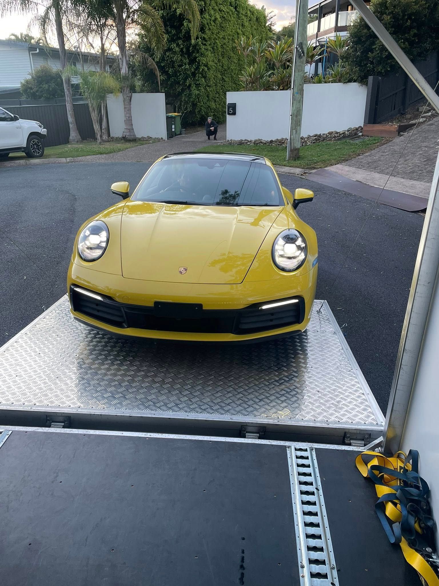 Yellow Porsche 911 on a flatbed truck, parked on a street — Full Throttle Enclosed Car Transport in Kilmore, VIC