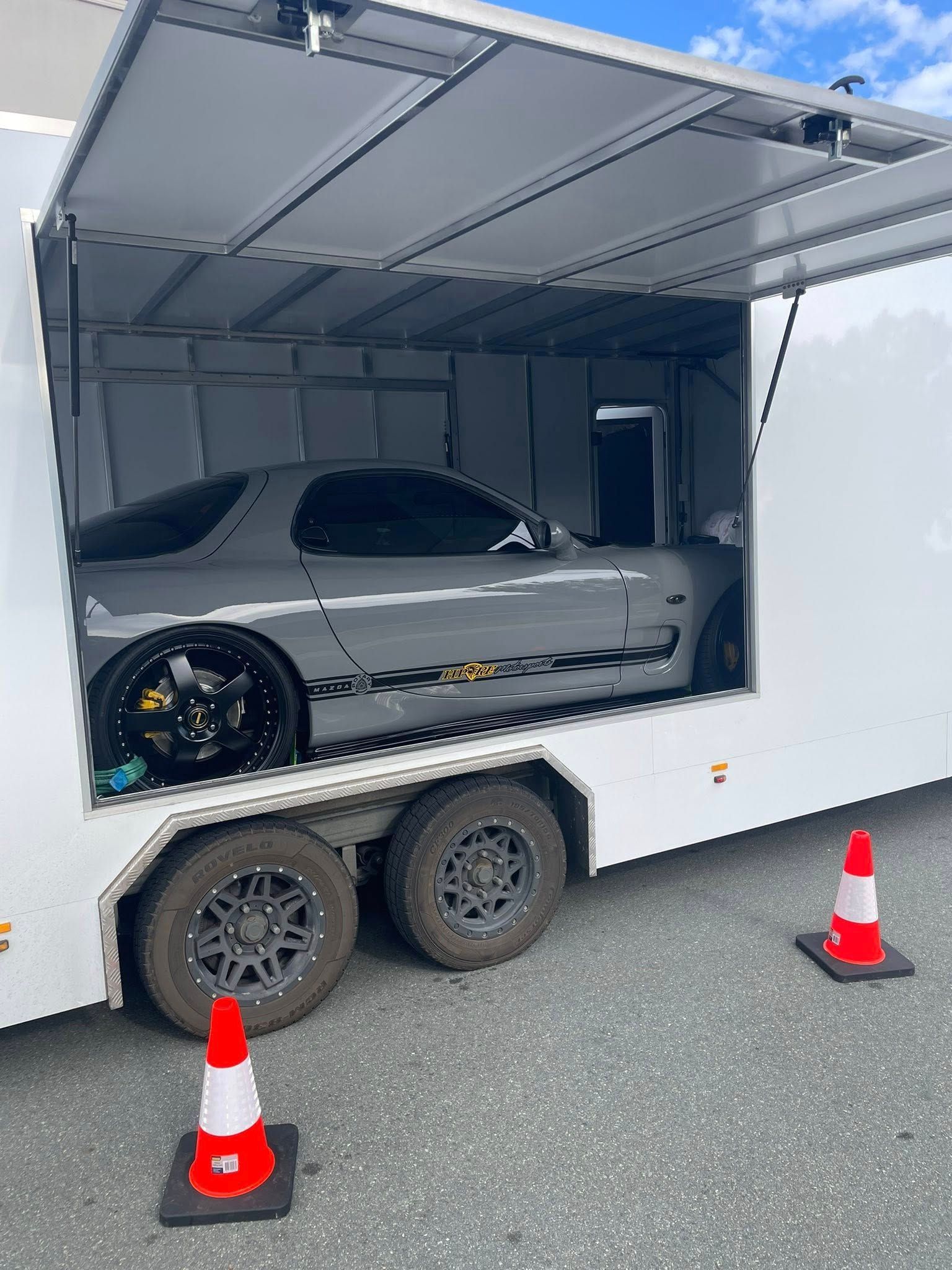 Grey Sports Car Inside a White Trailer, Cones in Front — Full Throttle Enclosed Car Transport in Sunshine Coast, QLD