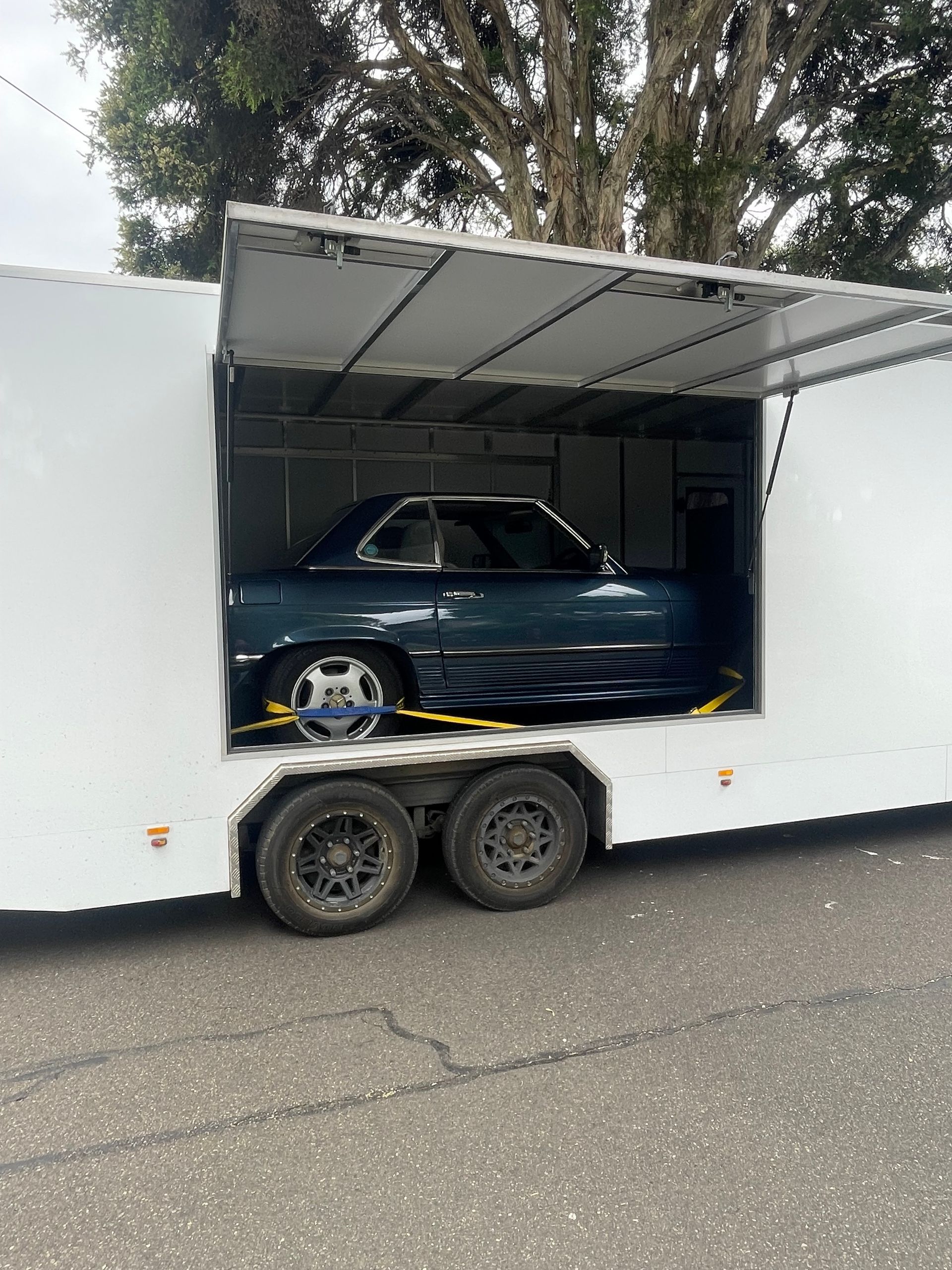 White car carrier trailer with a blue car inside, parked outdoors with the side door open Full Throttle Enclosed Car Transport in Kilmore, VIC