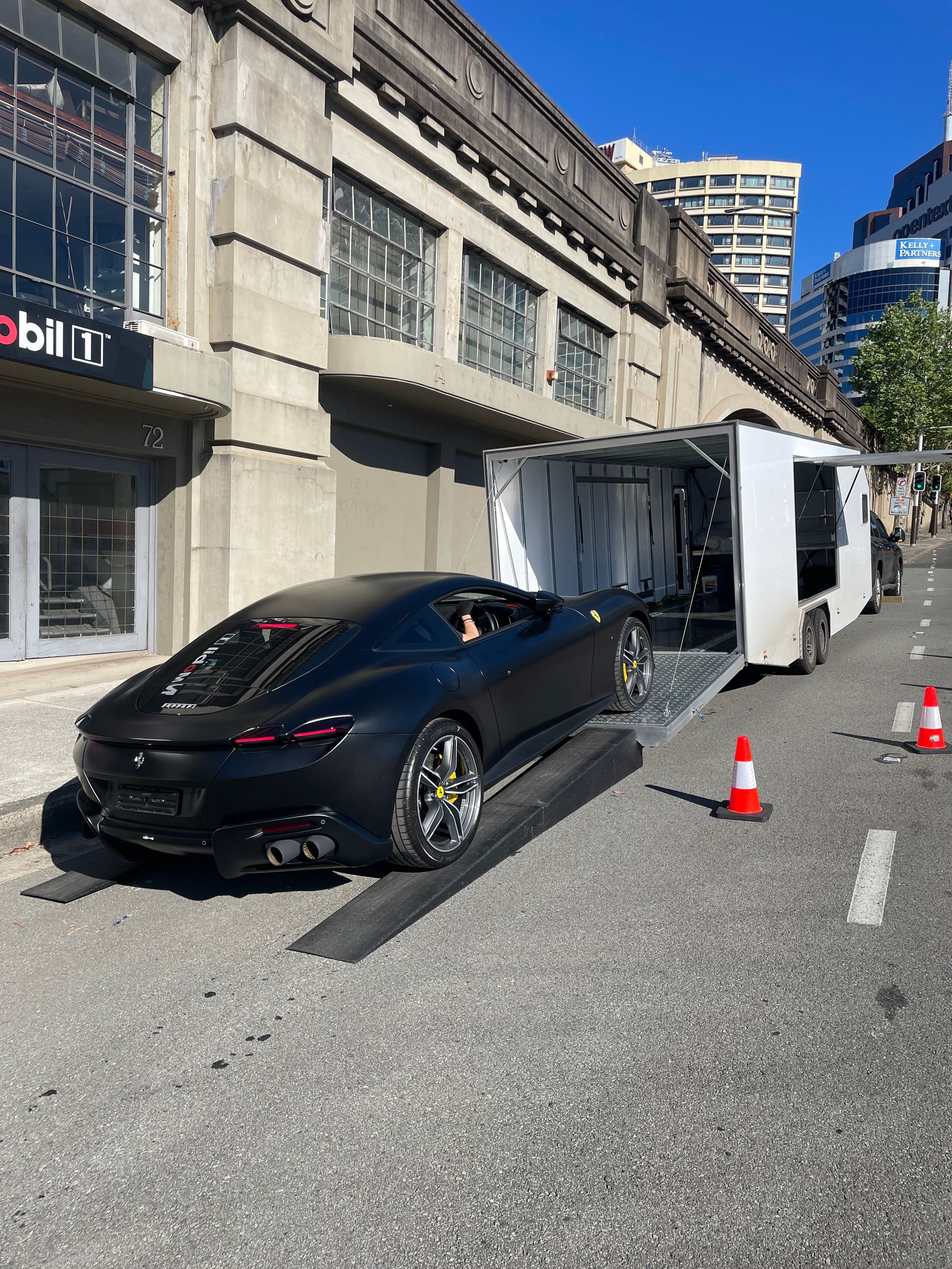 Black sports car crashed into an overturned white truck on a city street, with traffic cones around the wreck. Full Throttle Enclosed Car Transport in Kilmore, VIC