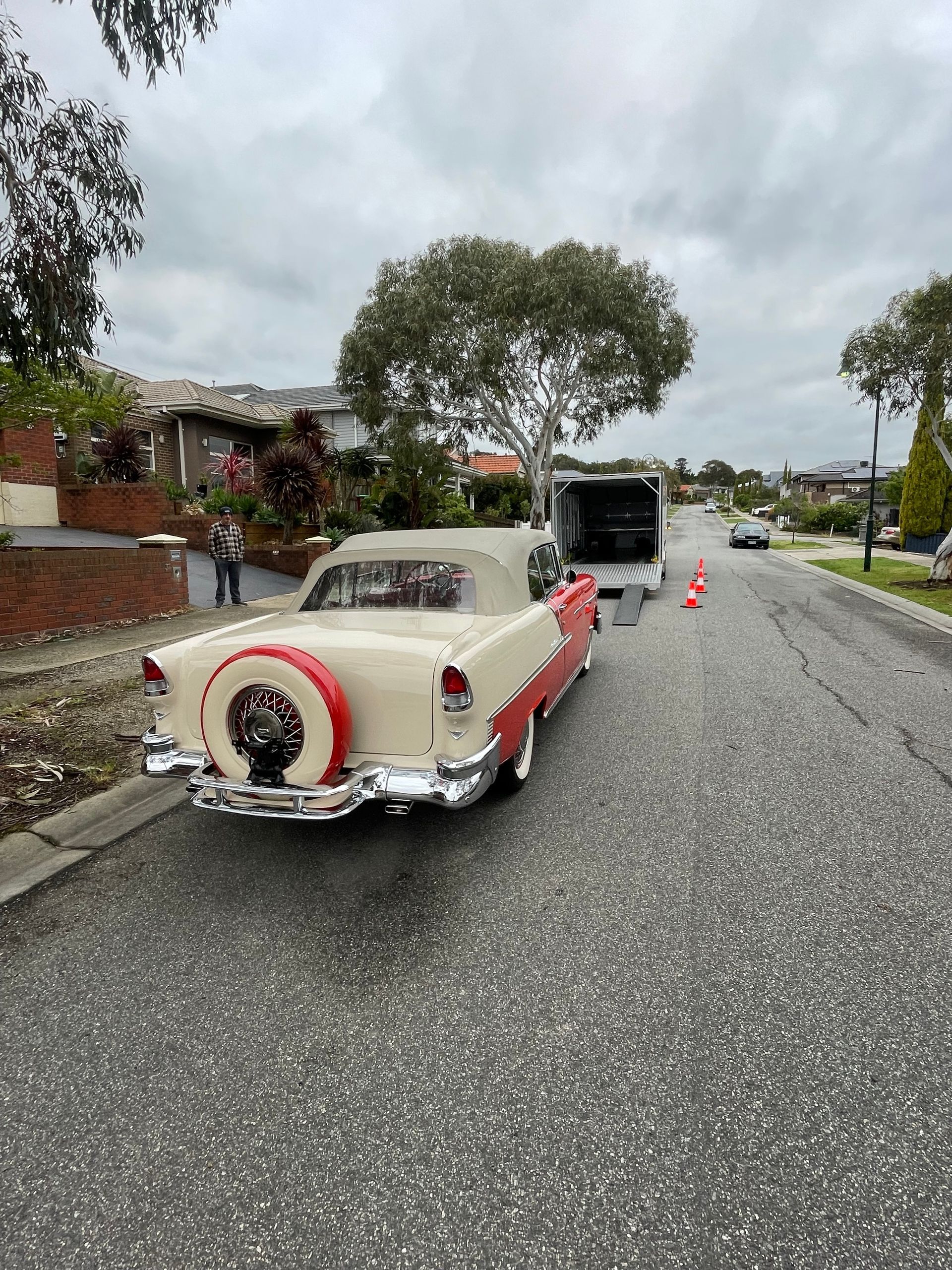Classic cream-colored car parked on a wet street with cones and an open black trailer behind it. - Full Throttle Enclosed Car Transport in Kilmore, VIC