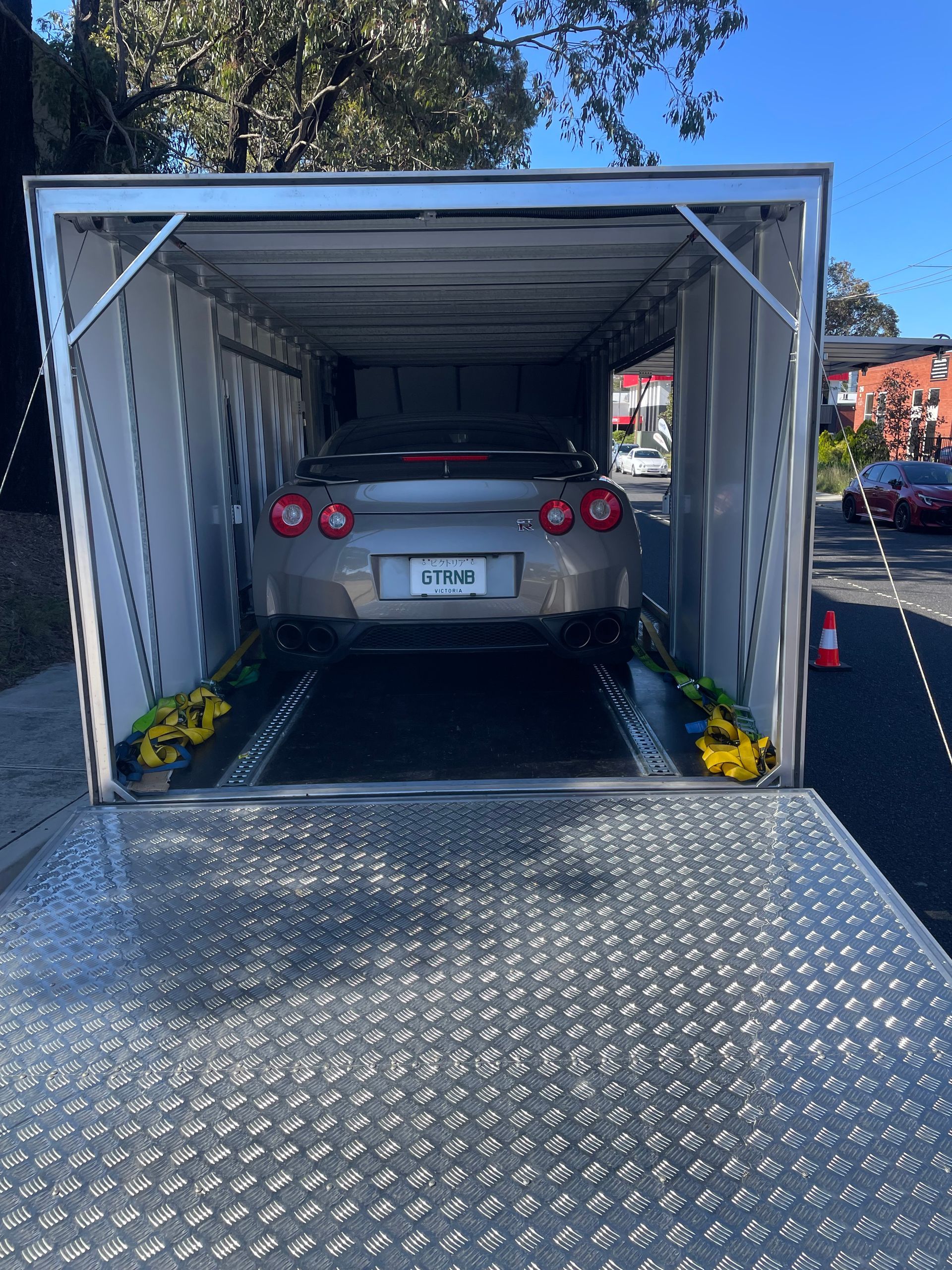 Car loaded inside a silver car carrier trailer with the rear ramp down. - Full Throttle Enclosed Car Transport in Kilmore, VIC