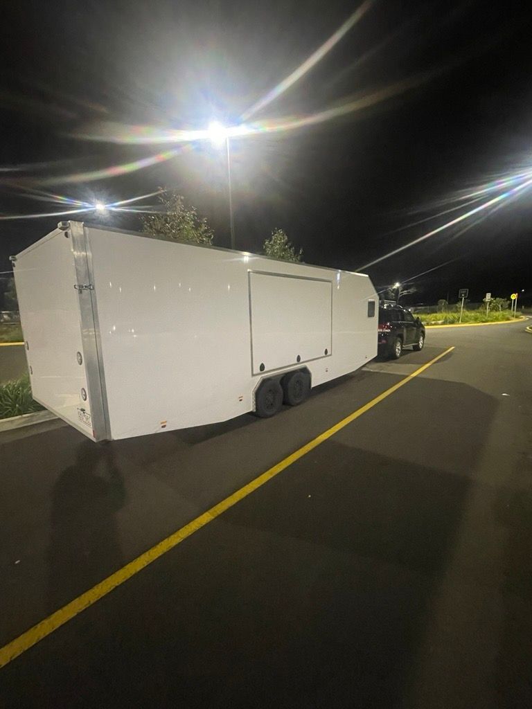 White enclosed trailer parked at night next to a black truck — Full Throttle Enclosed Car Transport in Kilmore, VIC