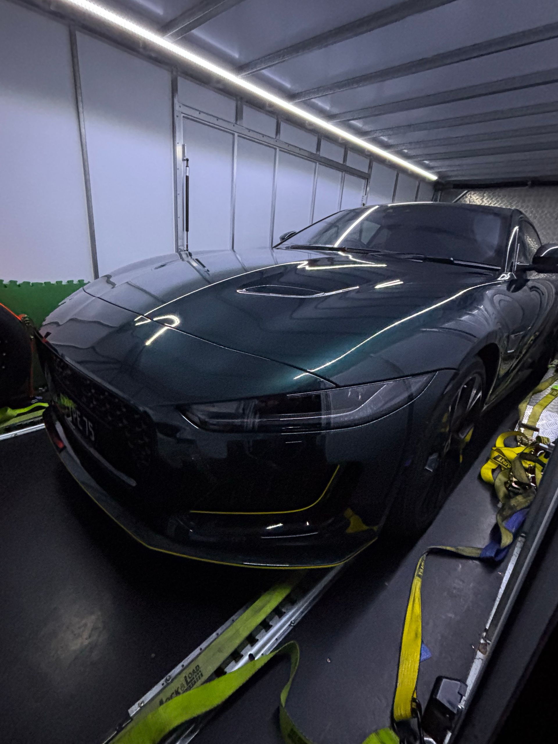 Black sports car in a garage, shown from the front with reflective hood and headlights. -Full Throttle Enclosed Car Transport in Kilmore, VIC