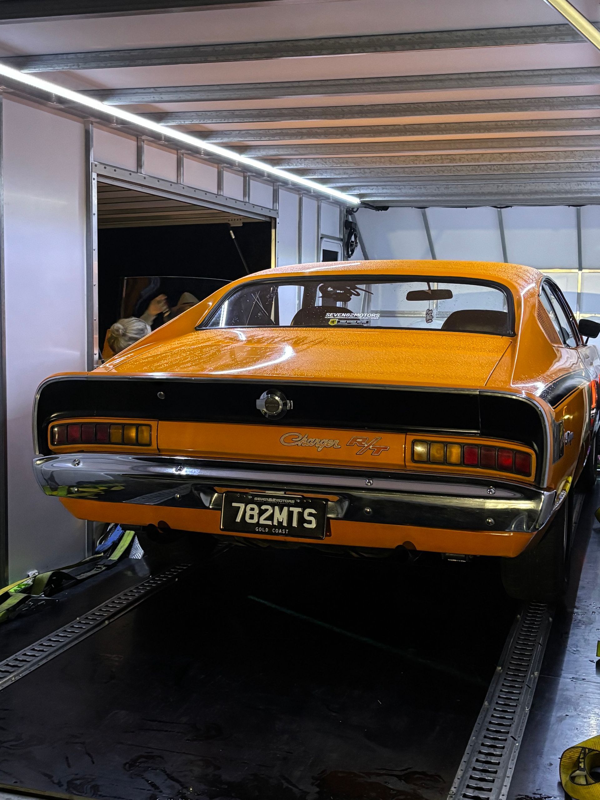 Orange classic muscle car on a trailer inside a garage, rear view with license plate visible - Full Throttle Enclosed Car Transport in Kilmore, VIC