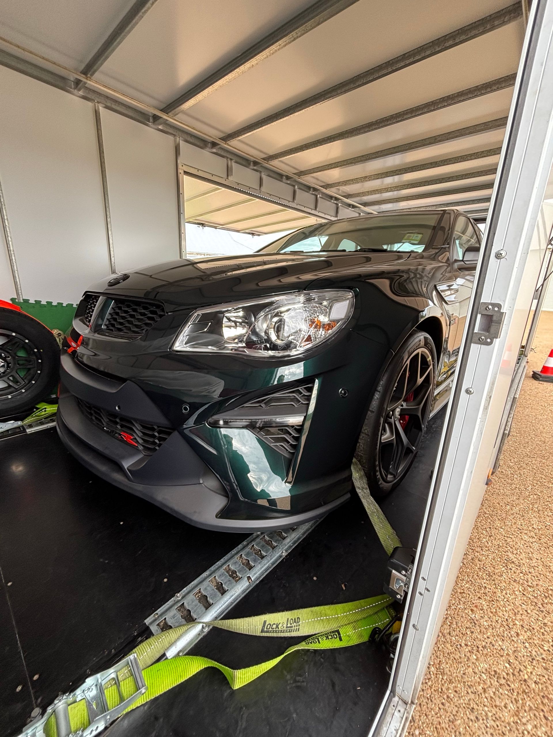Black sports car strapped in a trailer under a canopy -Full Throttle Enclosed Car Transport in Kilmore, VIC