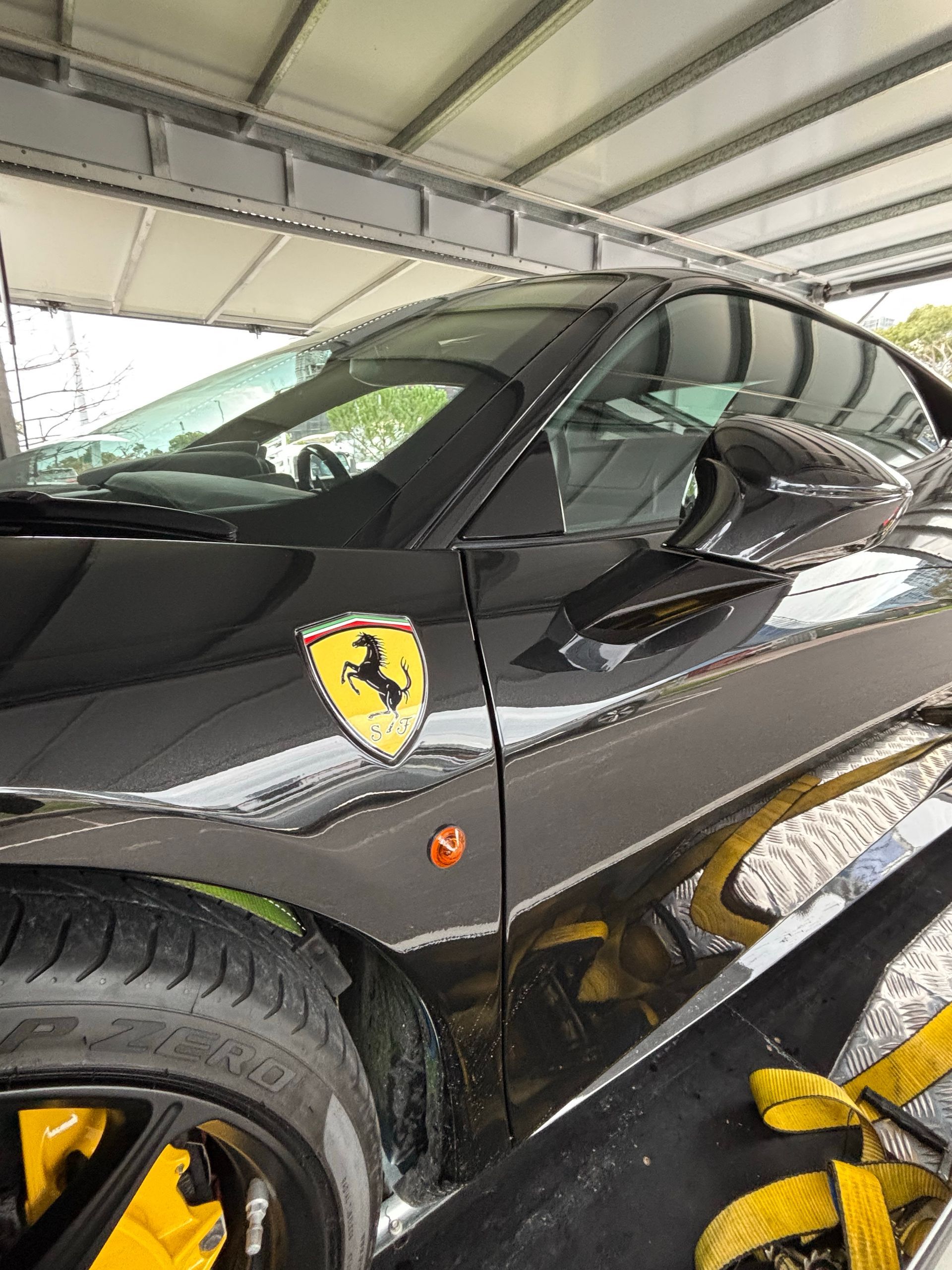 Black Ferrari sports car in a garage, close-up of the front side with yellow wheels and shield emblem - Full Throttle Enclosed Car Transport in Kilmore, VIC