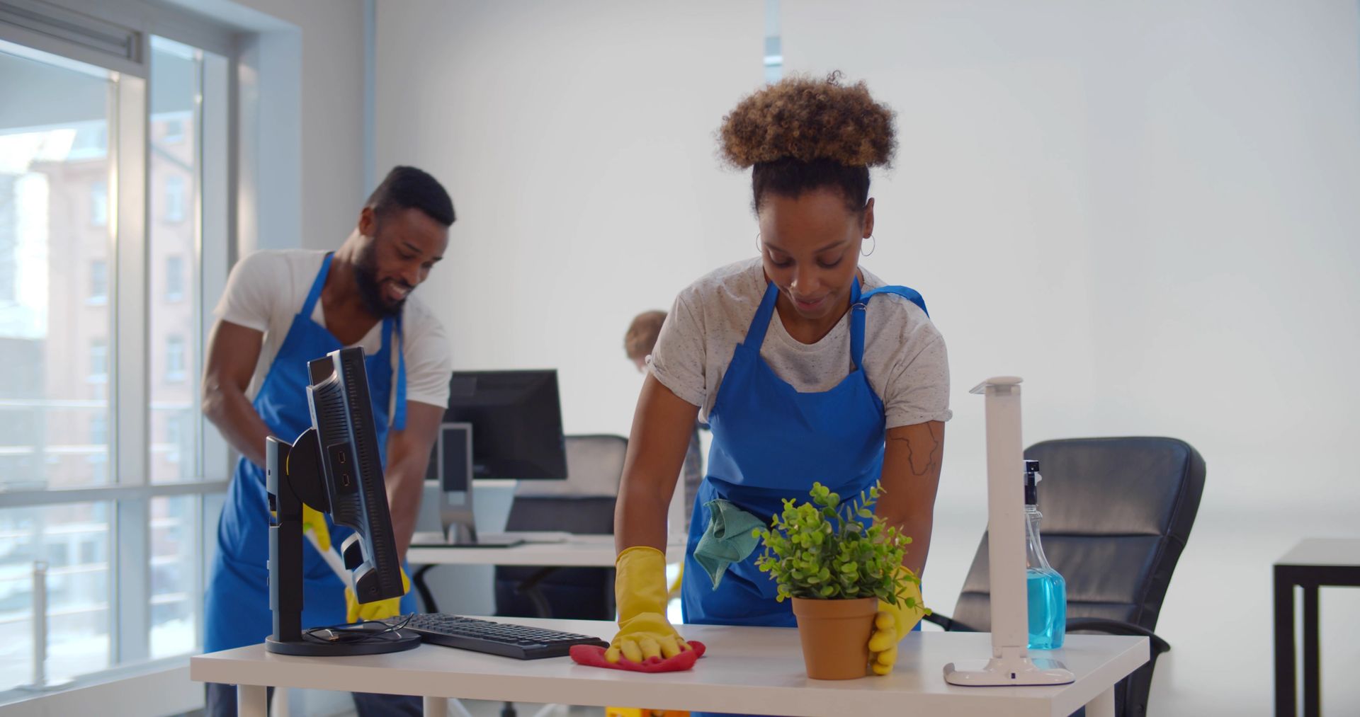 A man and a woman are cleaning a desk in an office.