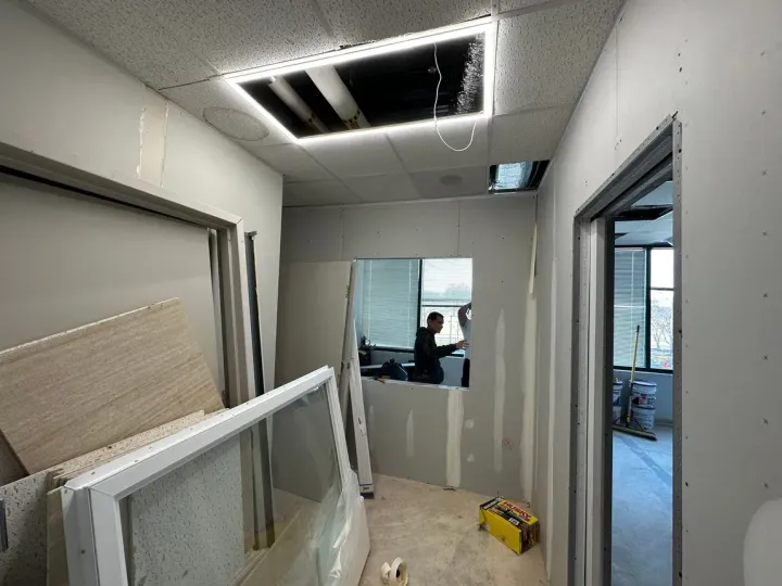 A man is working on a wall in a room with a light on the ceiling.