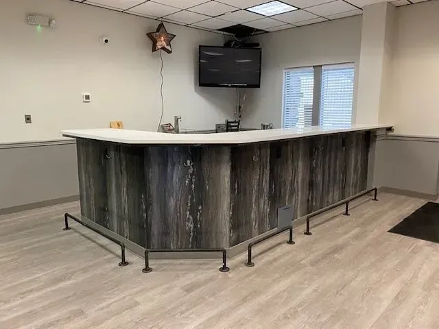 A long wooden bar in a room with a television on the wall.