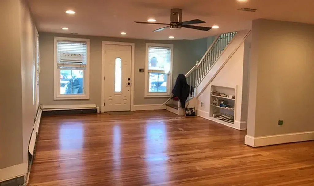 An empty living room with hardwood floors and a ceiling fan.