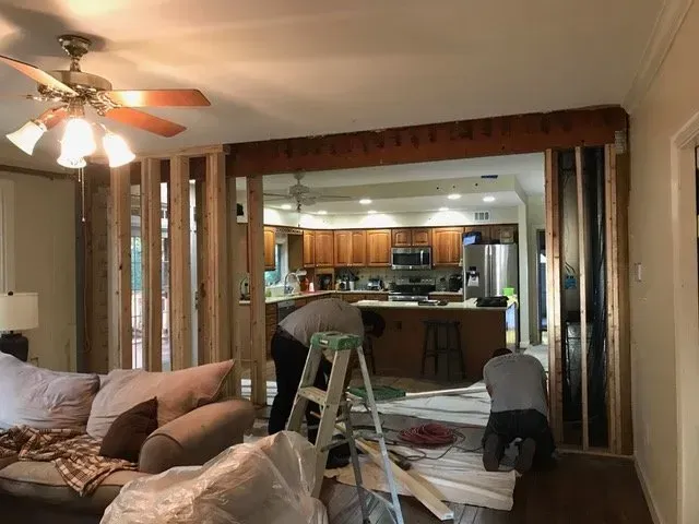 A man is working on a wall in a living room.