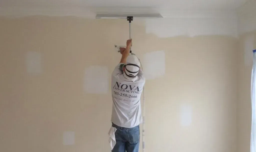 A man is hanging from the ceiling while painting a wall.