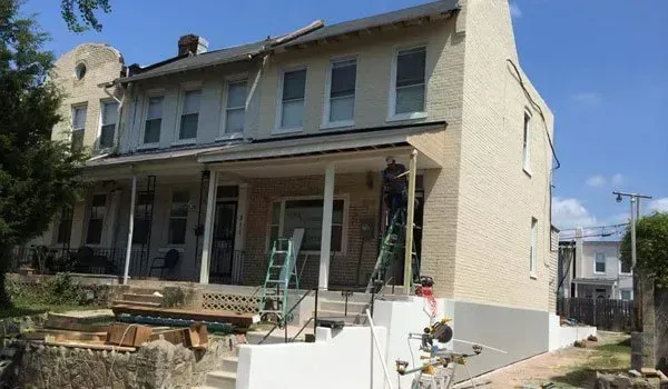 A house is being painted in a city on a sunny day.