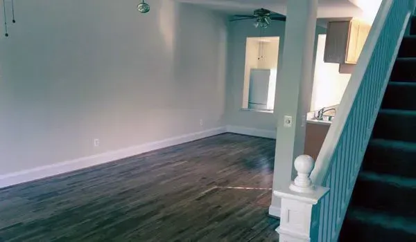 An empty living room with hardwood floors and stairs leading up to the second floor.
