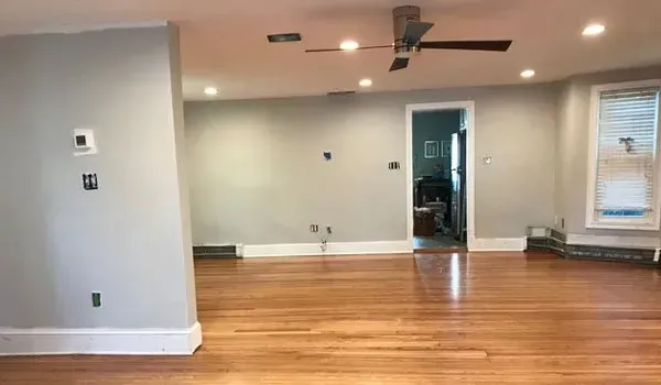 An empty living room with hardwood floors and a ceiling fan.