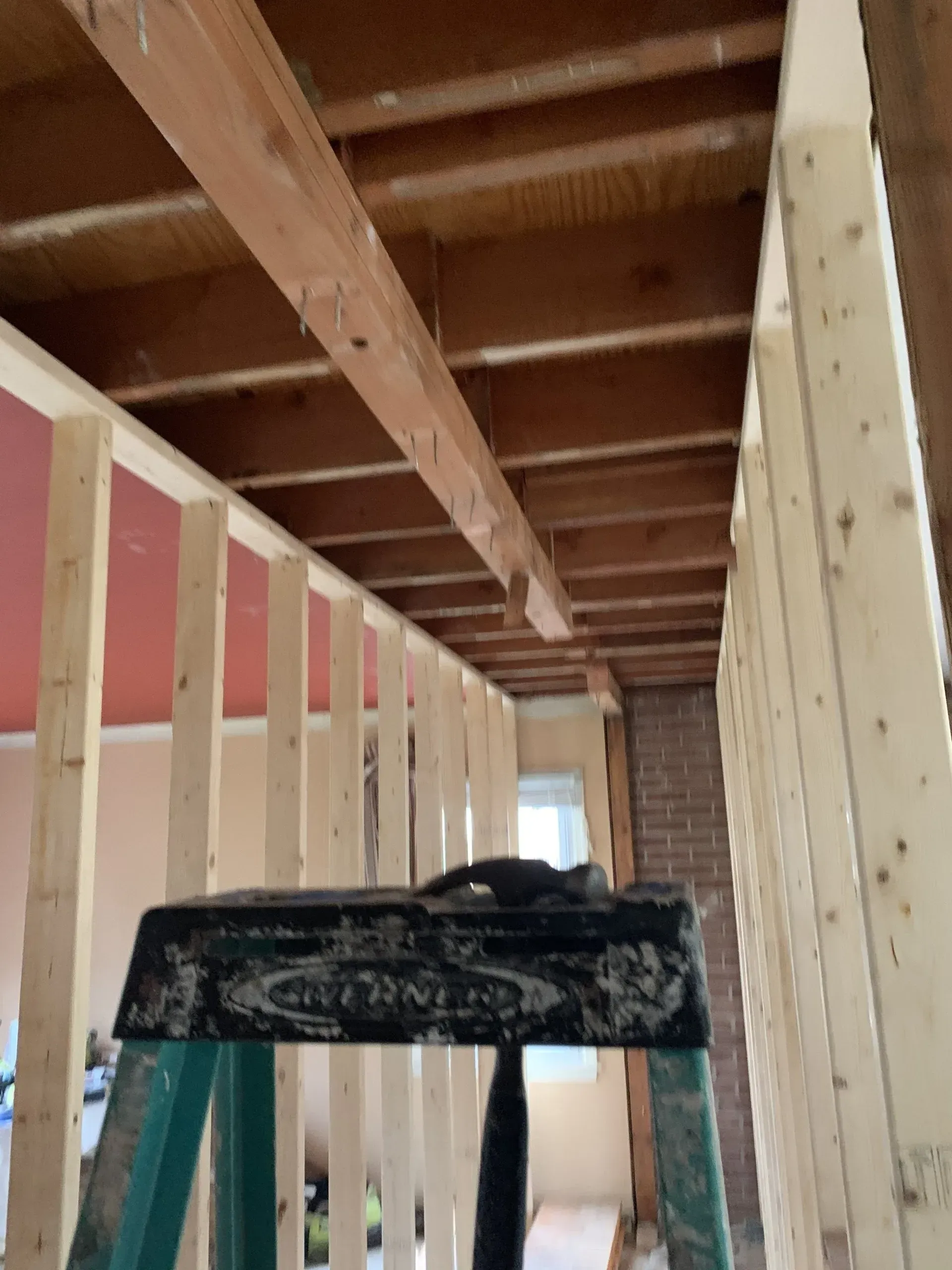 A ladder is sitting in the middle of a room under construction.