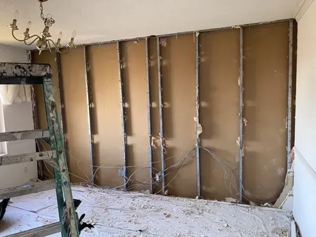 A room with a ladder and a chandelier hanging from the ceiling.