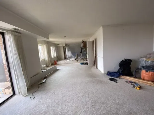A large empty room with a carpeted floor and a sliding glass door.
