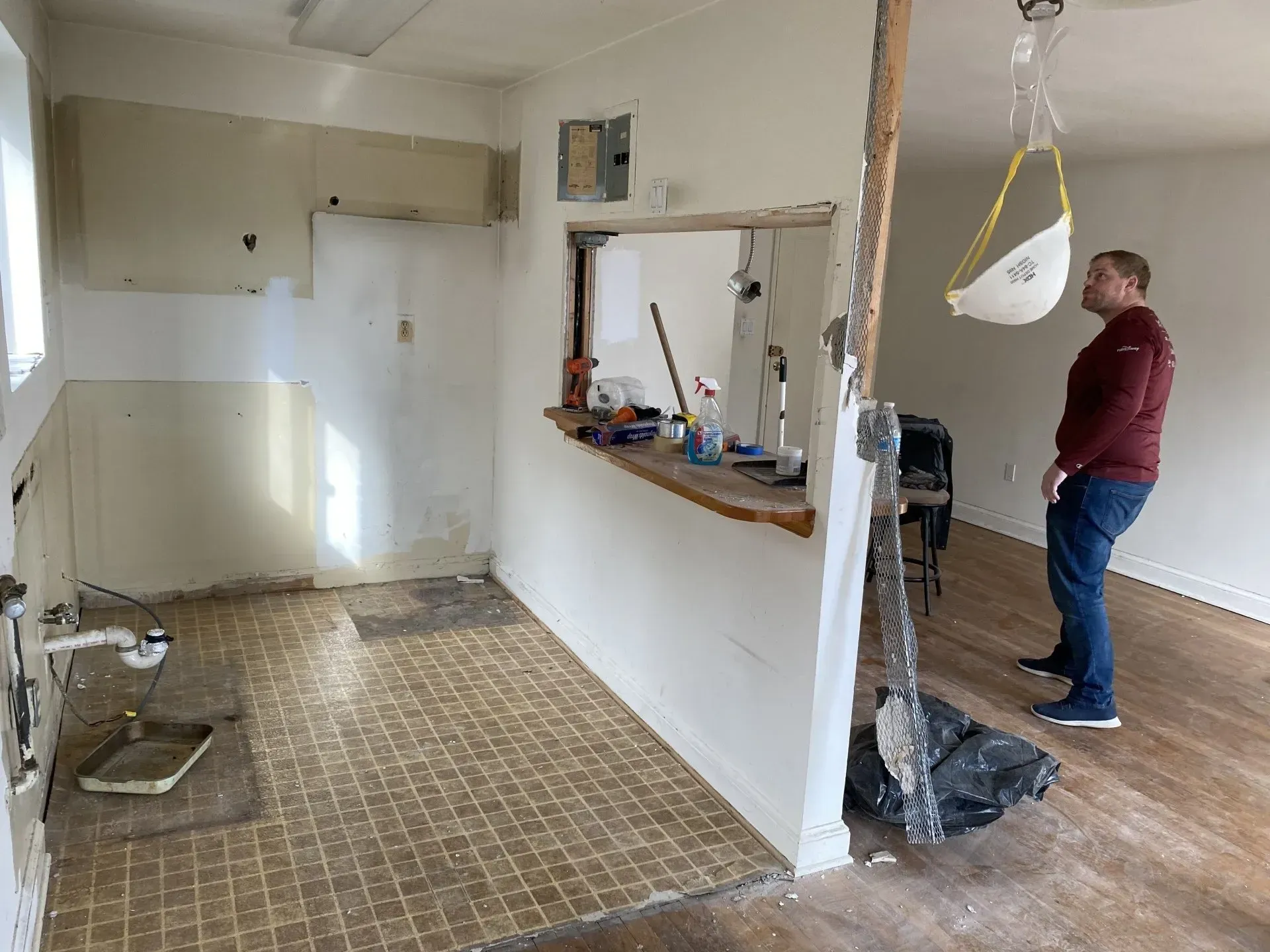A man wearing a mask is standing in an empty room.