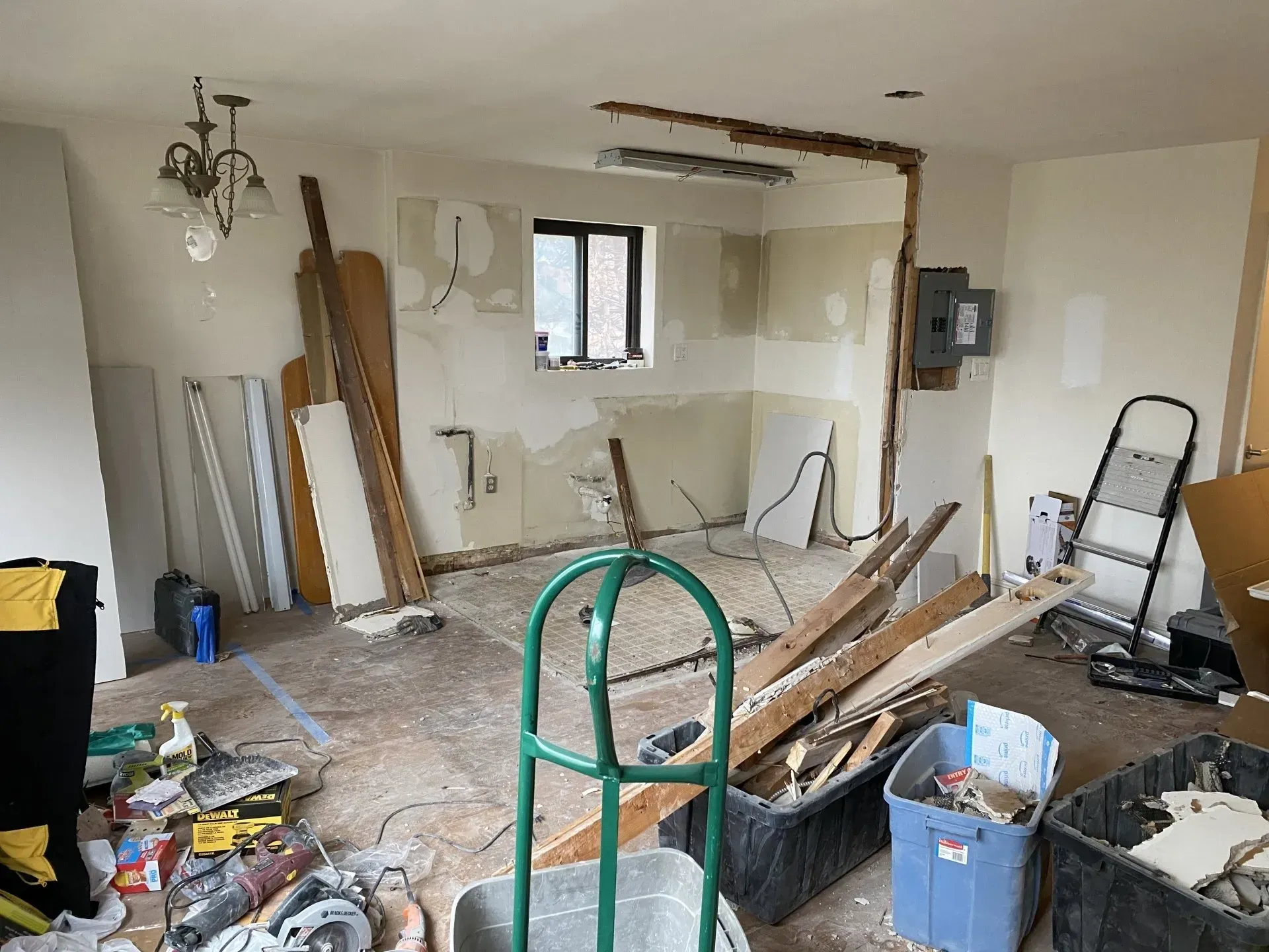 A room with a lot of junk in it and a green cart.