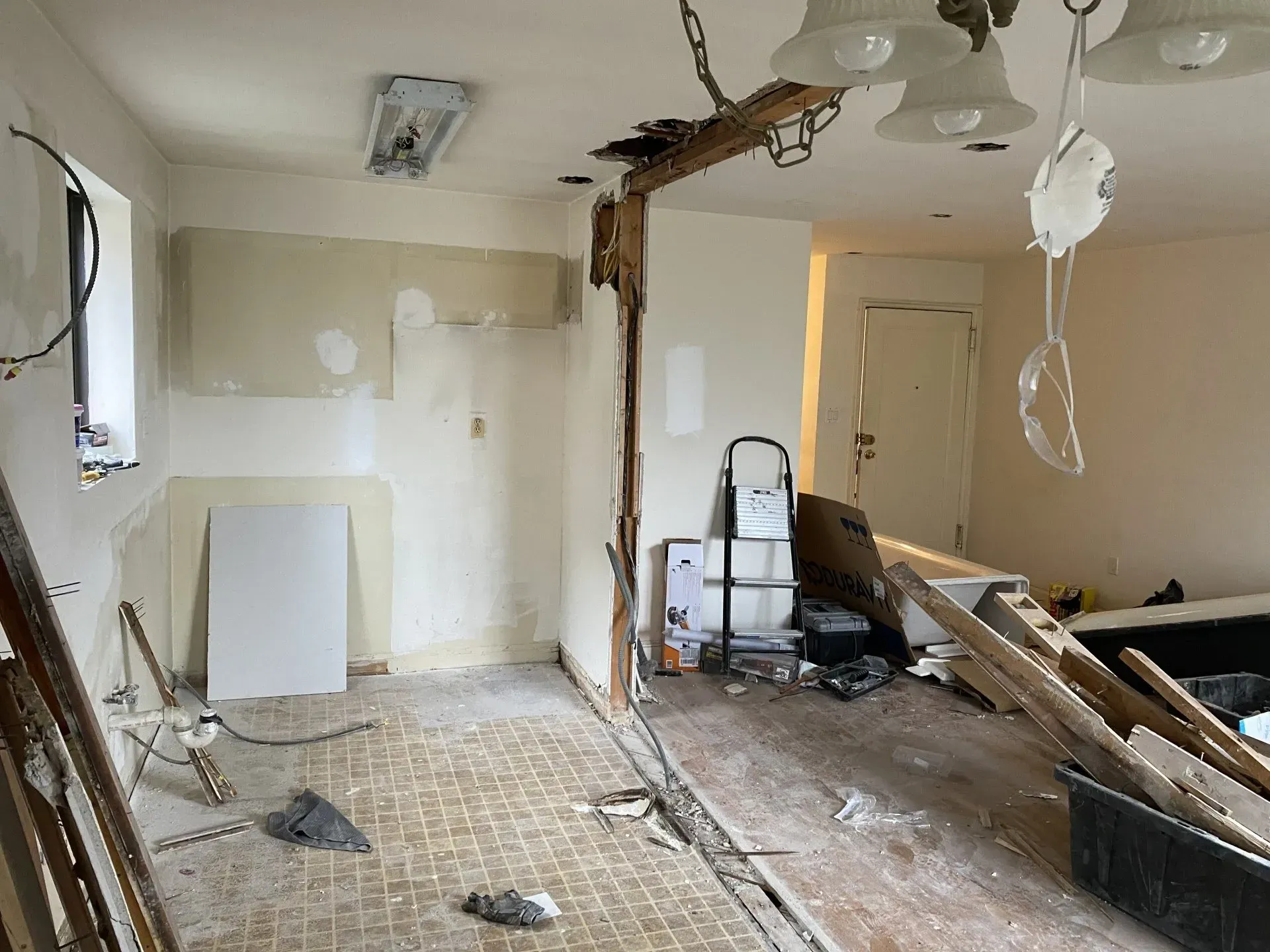A room with a broken wall and a chandelier hanging from the ceiling.