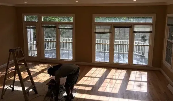 A man is bending over in an empty room with a ladder.