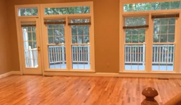 An empty room with hardwood floors and lots of windows.