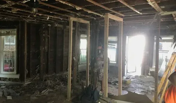 A man is standing in the middle of a room in a house under construction.