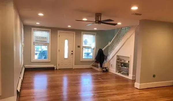 An empty living room with hardwood floors and a ceiling fan.